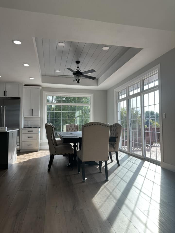 Finished dining area with shiplap tray ceiling, large windows, sliding glass door, and dark hardwood floors